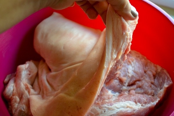 Raw pork with the skin cut is in a bowl.