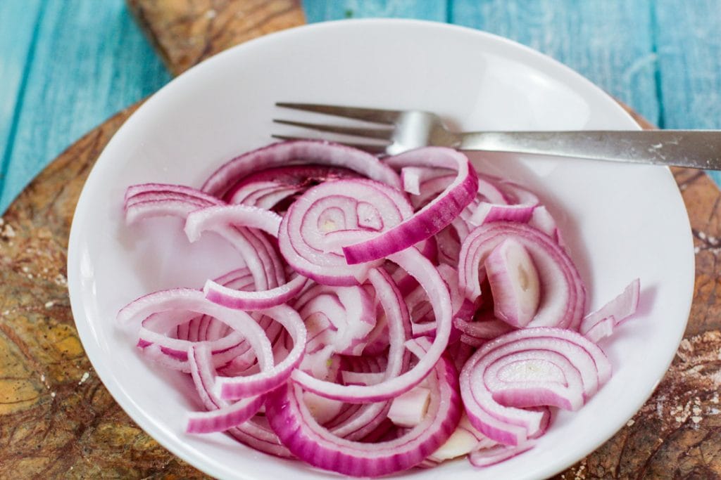 red onions with vinegar in a white bowl