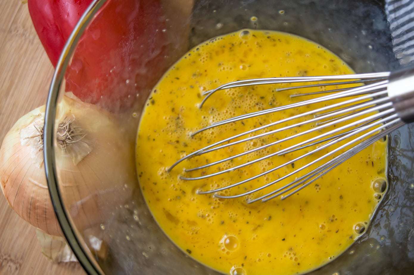 egg mixture in a glass container with a metal whisk