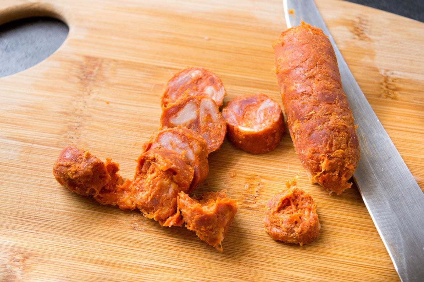 Chopped Spanish chorizo on a wooden cutting board.