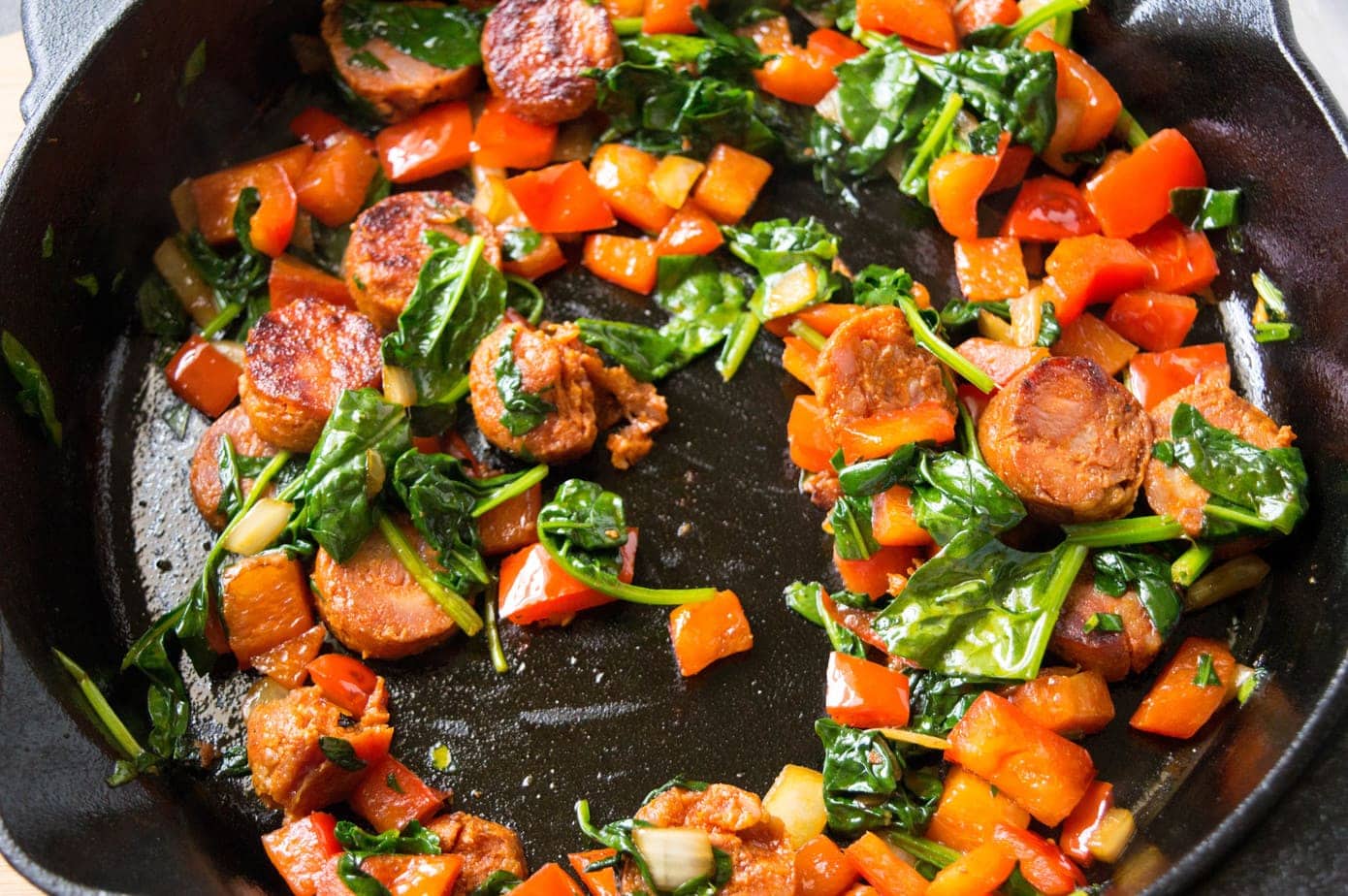 Sautéed onions, peppers, and spinach in a cast iron skillet.