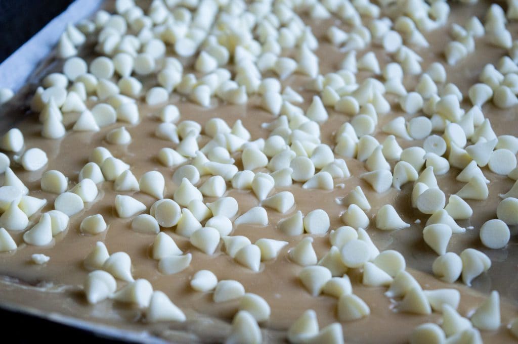 white chocolate chips on toffee in a pan