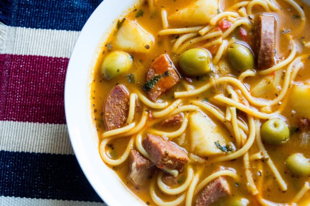 overhead shot of salami soup in a white bowl