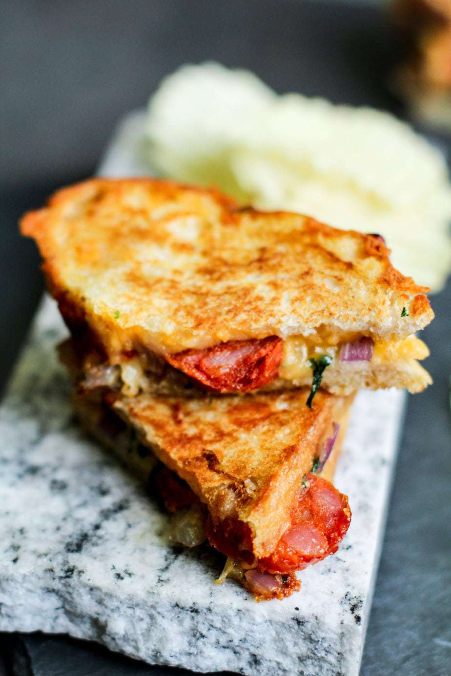 Deluxe grilled cheese filled with colorful veggies on a marble serving tray.