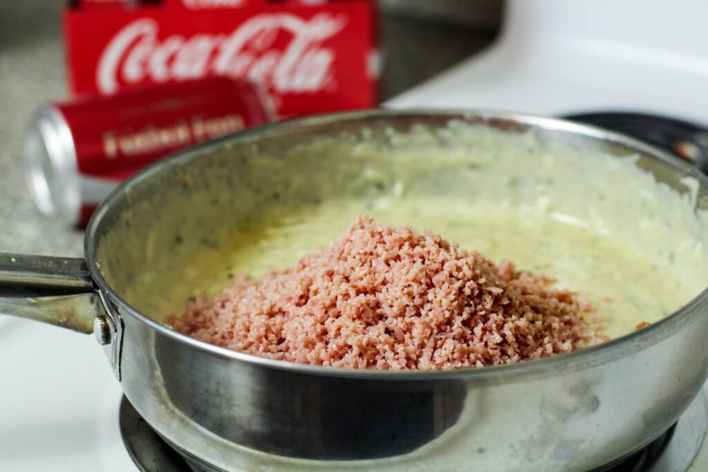 diced ham over a roux in a stainless steel pan