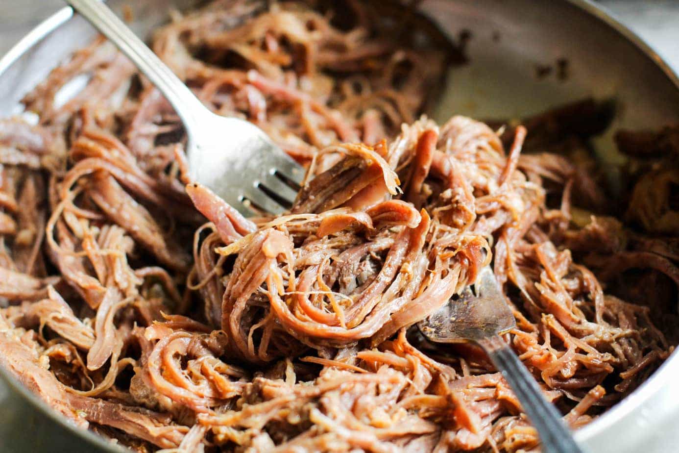 Ropa vieja being shredded with two forks