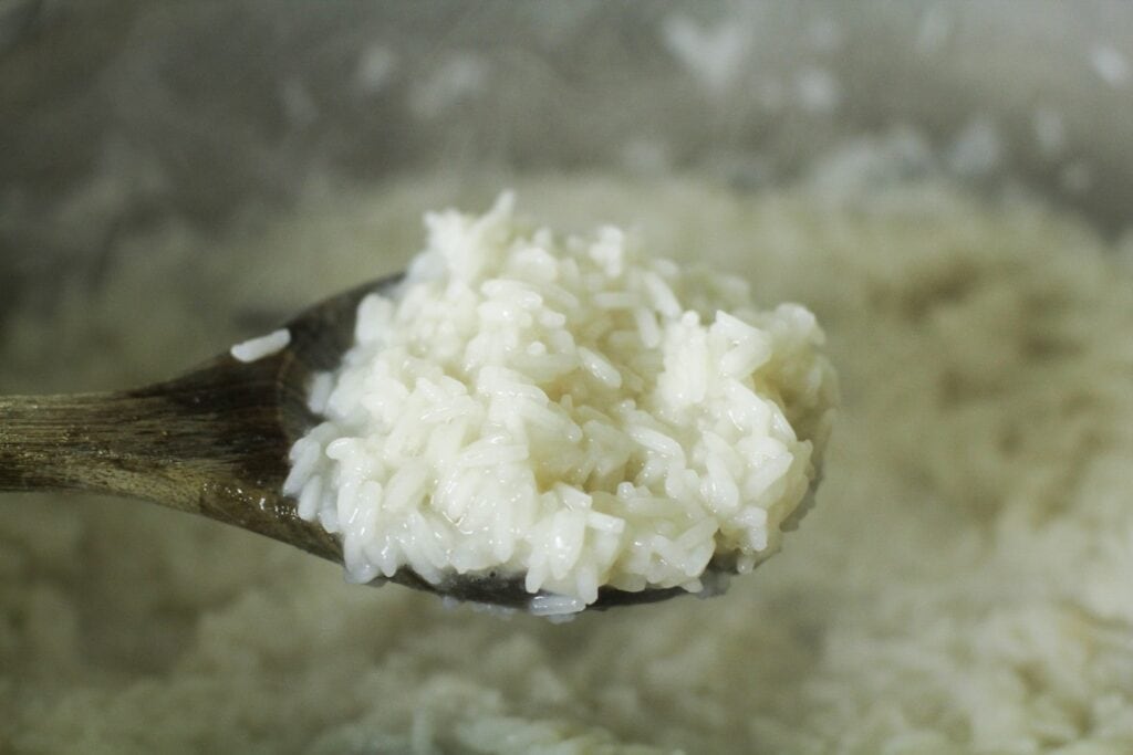 Al dente rice in a pot lifted by a spoon