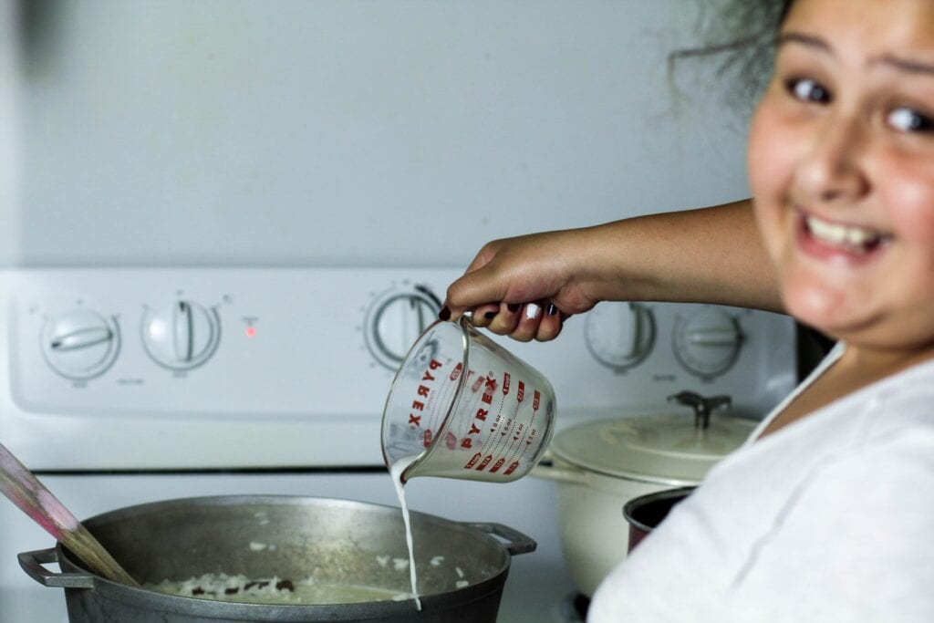 girl adding milk to rice pudding