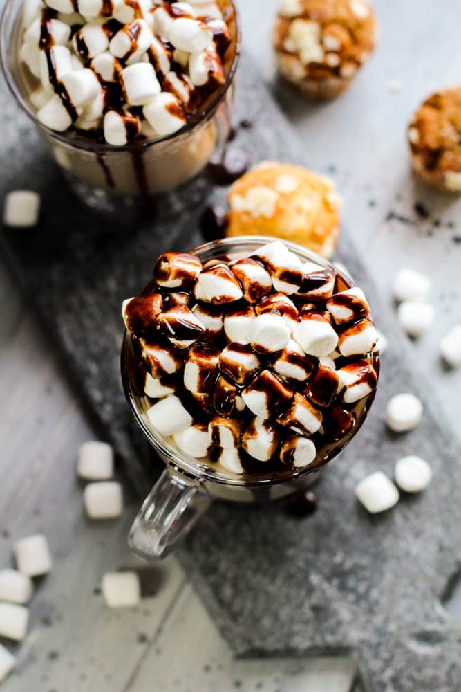 overhead shot of a glass cup with mini marshmallows and Hershey's syrup