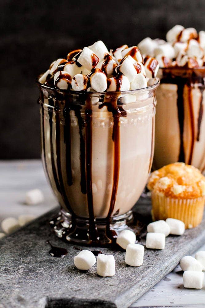 glass cup filled with chocolate coquito, marshmallows, and chocolate syrup