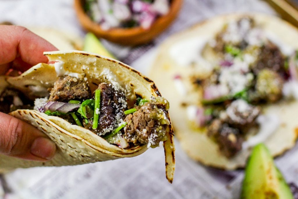 barbacoa tacos held in the air