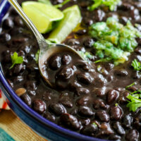 Cuban black beans with a metal spoon and lime wedges