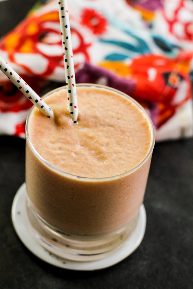 Papaya smoothie in a glass cup with two straws