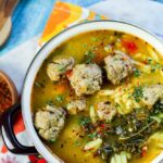 Spanish meatball soup in a purple pot with bright colored napkin in the background
