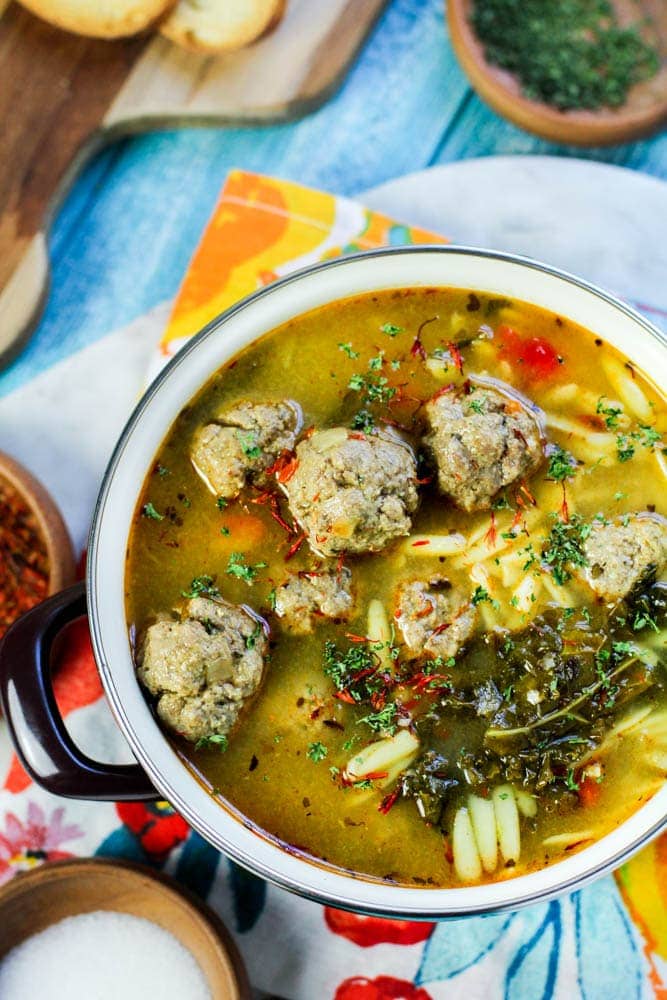 Spanish meatball soup in a purple pot with bright colored napkin in the background