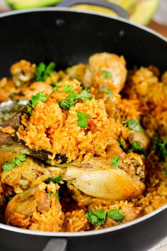 Cooked yellow rice in a pot with cooked drumsticks.