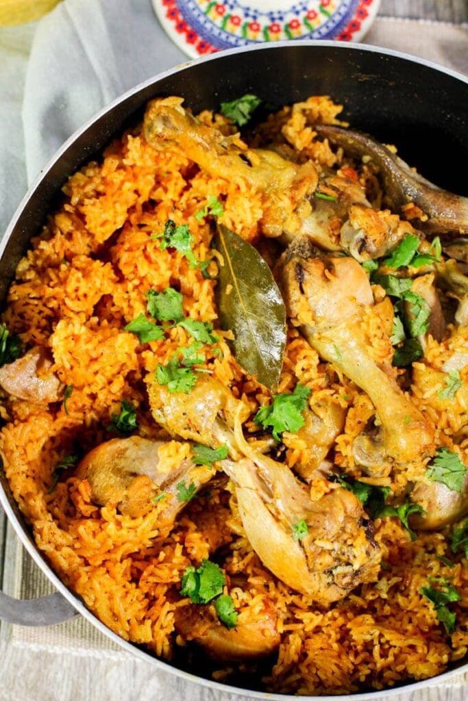  Spanish rice, cooked chicken, and a bay leaf in a black pot.