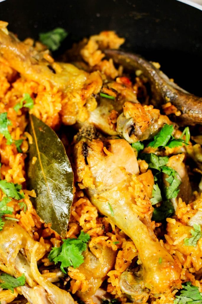 cooked chicken with a bay leaf on a bed of Spanish rice