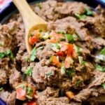 Refried beans in a blue bowl with pico de gallo on top