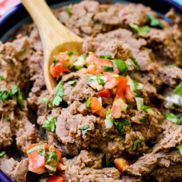 Refried beans in a blue bowl with pico de gallo on top