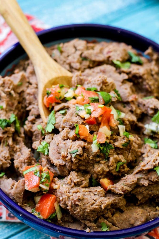 Refried beans in a blue bowl with pico de gallo on top