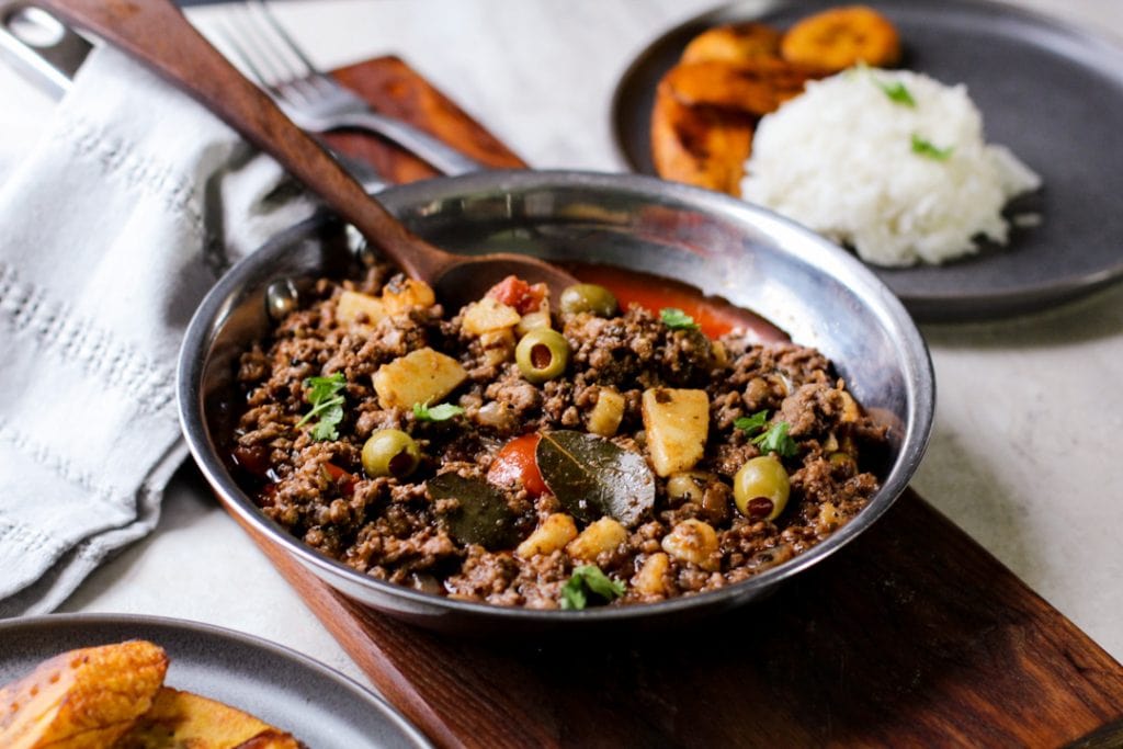 picadillo in a pan with a wooden spoon