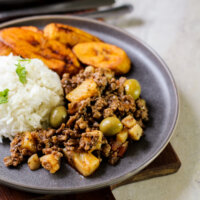 picadillo with write rice and plantains on a gray plate