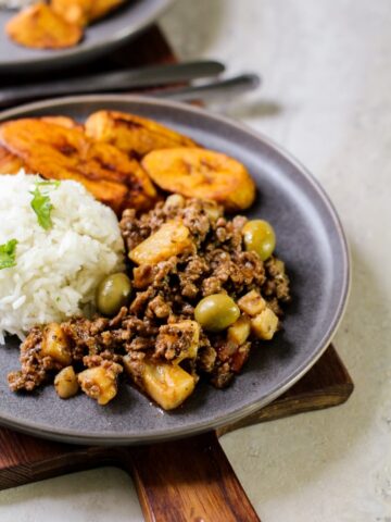 picadillo with write rice and plantains on a gray plate
