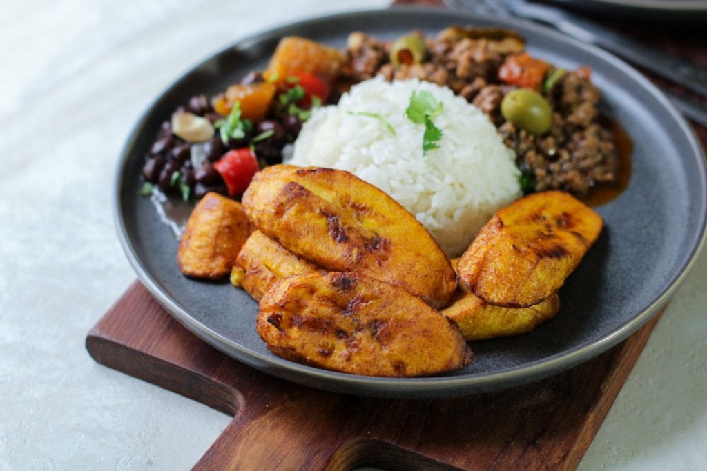 platano maduros with white rice on a cutting board and gray plate