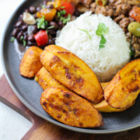 fried plantains on a gray plate with rice and beans