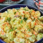 Puerto Rican potato salad in a blue bowl with cilantro as garnish