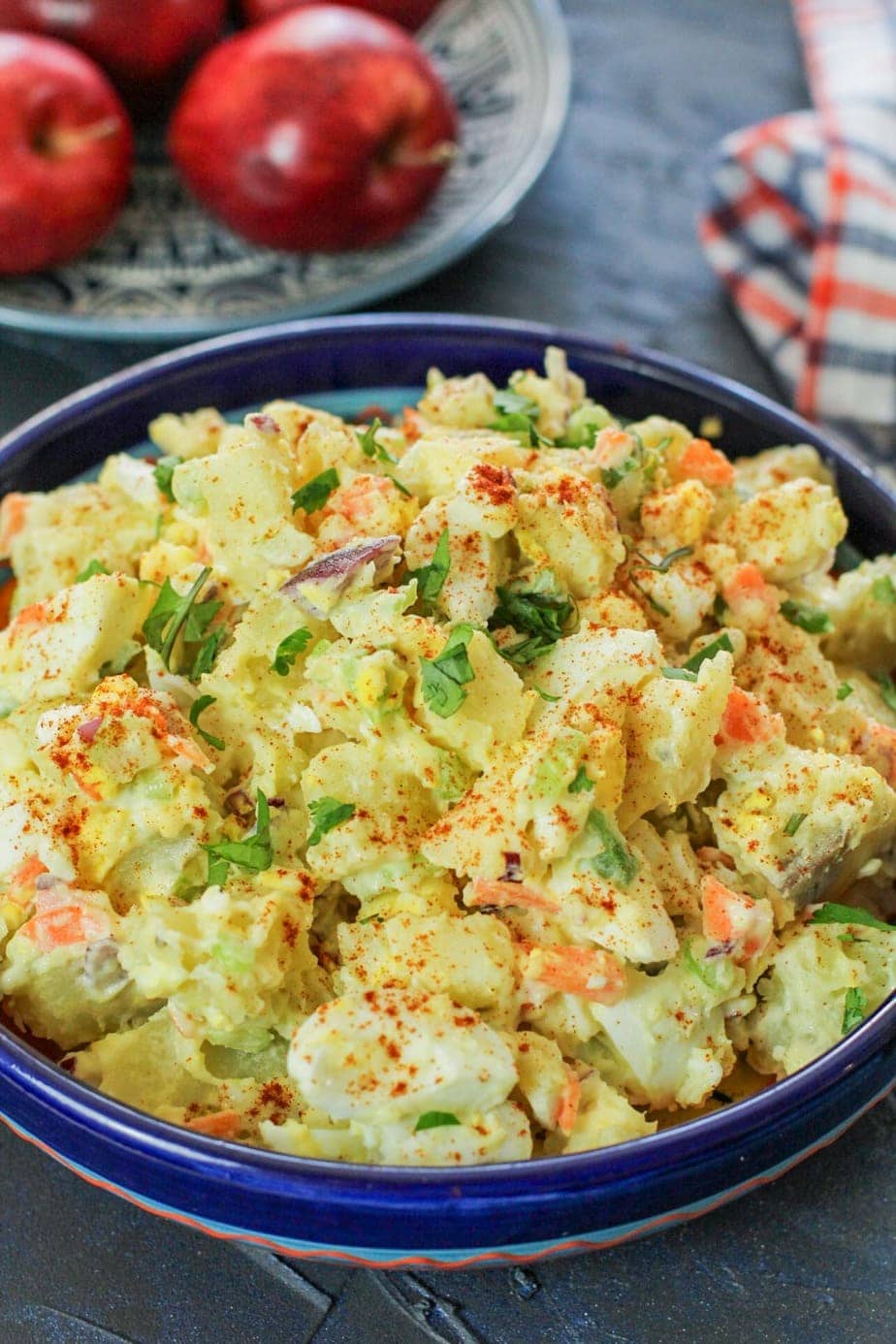 Puerto Rican potato salad in a blue bowl with cilantro as garnish