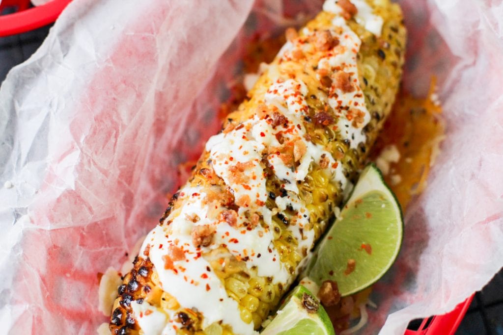 grilled corn on wax paper with lime wedges