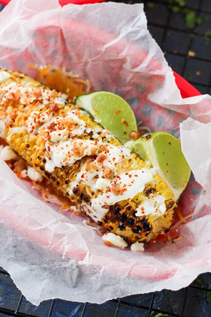 street corn with bacon and lime wedges