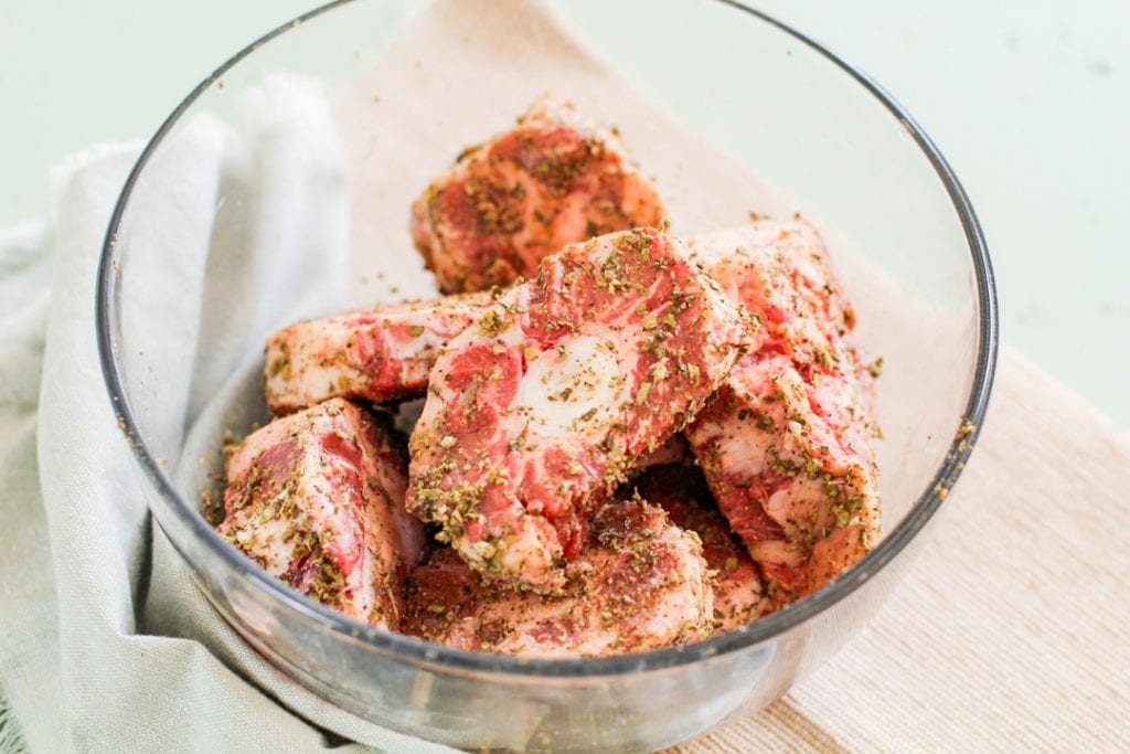 seasoned oxtails in a glass bowl