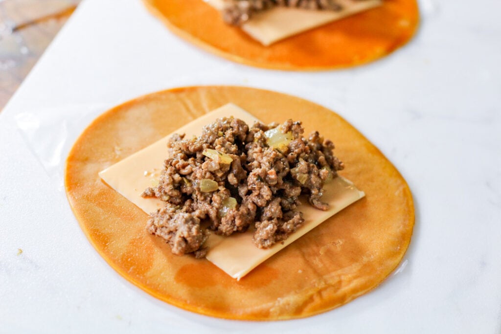 open disc with slice of cheese and picadillo