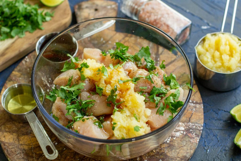 pineapple and raw chicken in a glass bowl