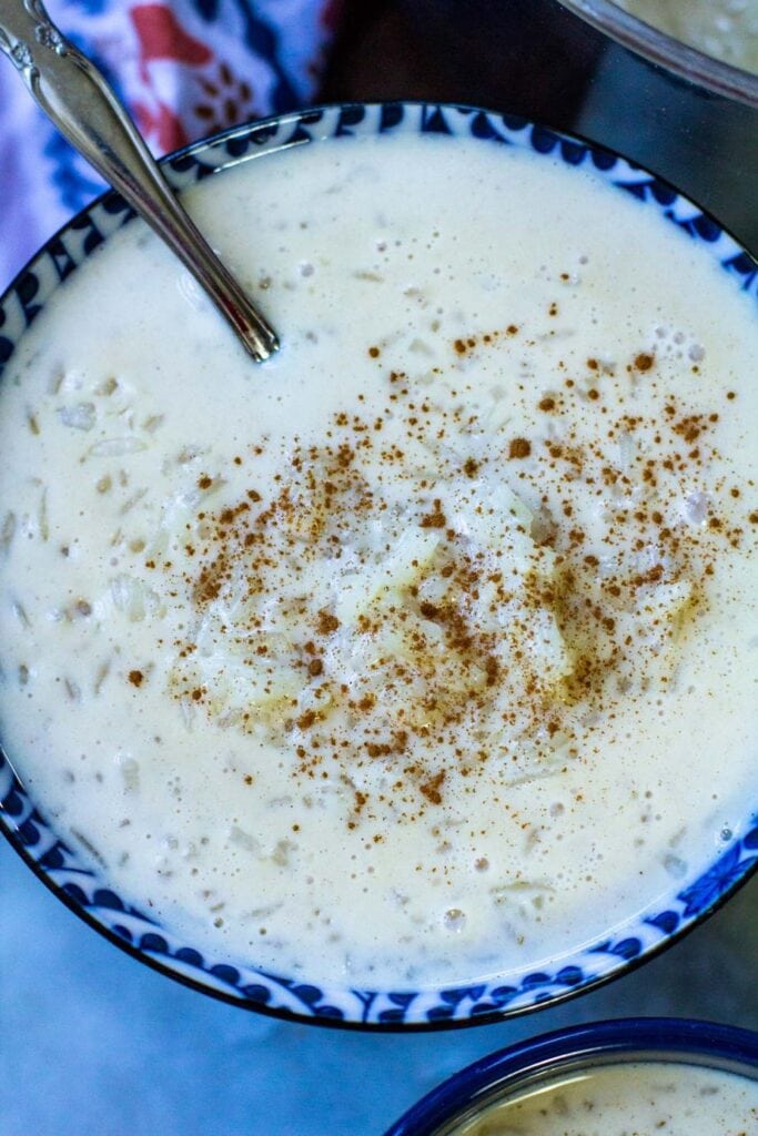 close up shot of a blue bowl filled with rice and milk with a sprinkle of ground cinnamon