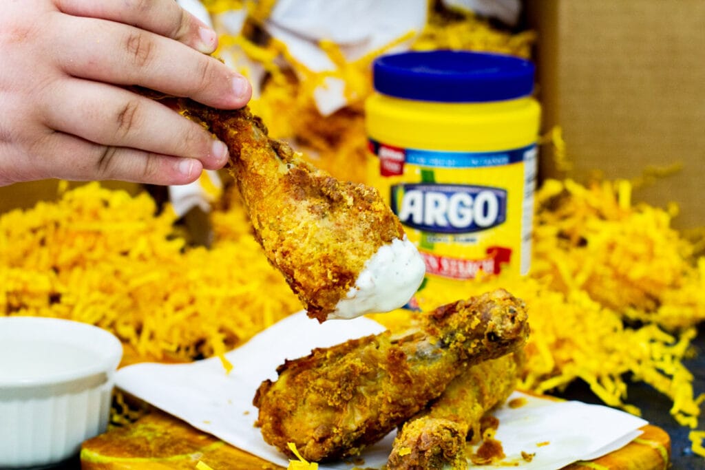 Fried chicken being dipped into ranch.