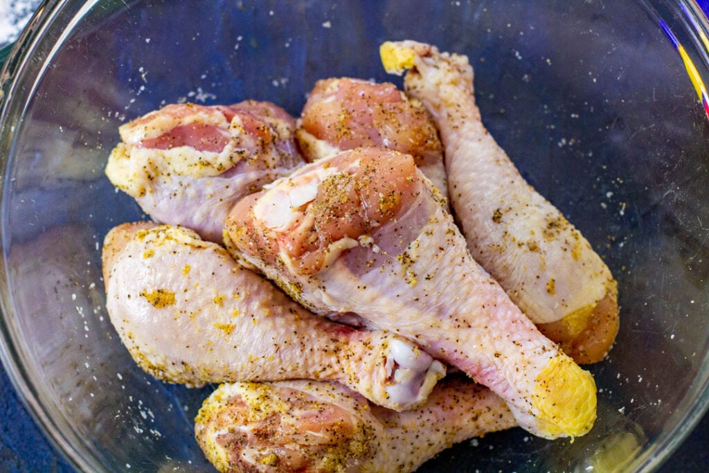 raw seasoned chicken in glass bowl