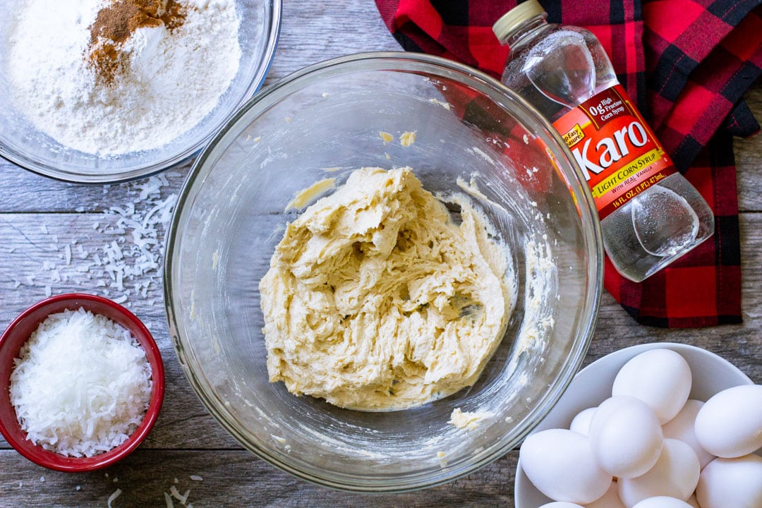 Butter, sugar, and egg mixed together in a clear bowl for coconut cookies.