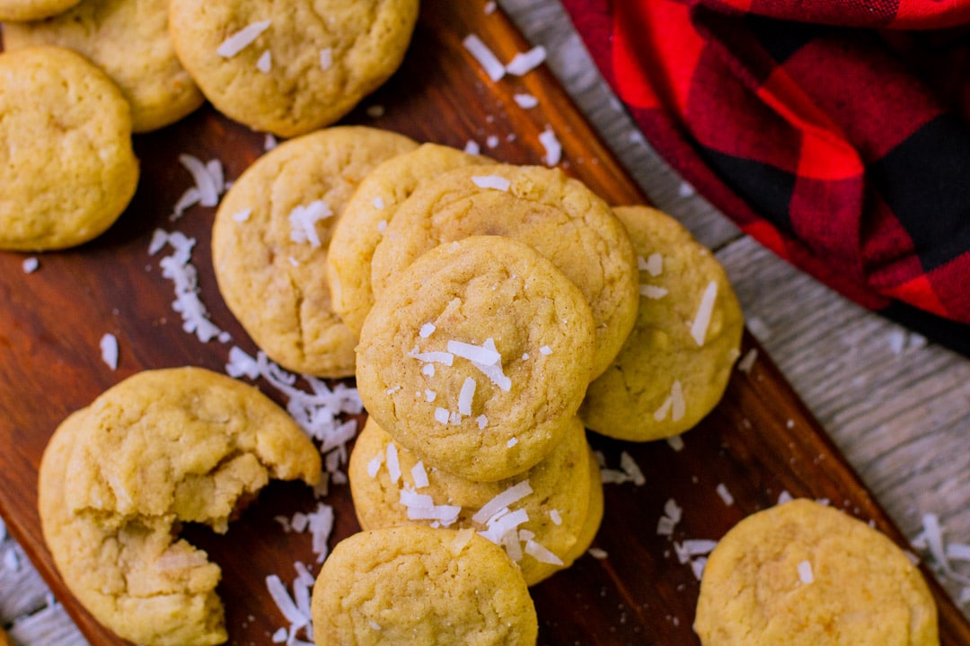 A batch of round cookies with shredded coconut flakes scattered over it.