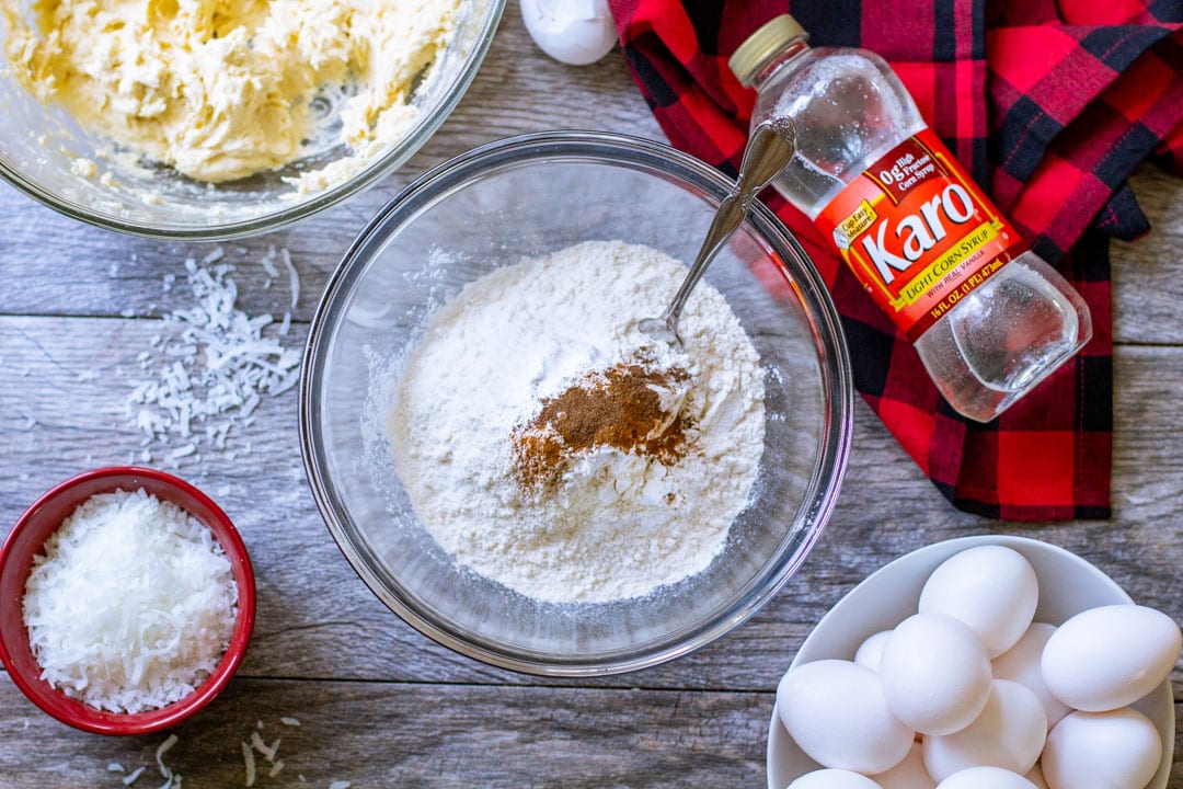 Dry cookie ingredients, such as flour and spices inside of a glass bowl.