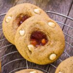 guava sugar cookies with white chocolate chips lined up on a wire rack
