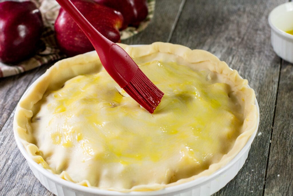 egg yolk being brushed over the apple pie