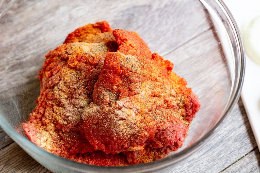 steak with seasonings in a glass bowl