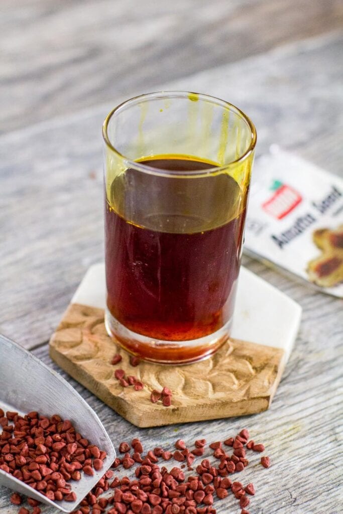 achiote oil in a glass cup on a coaster