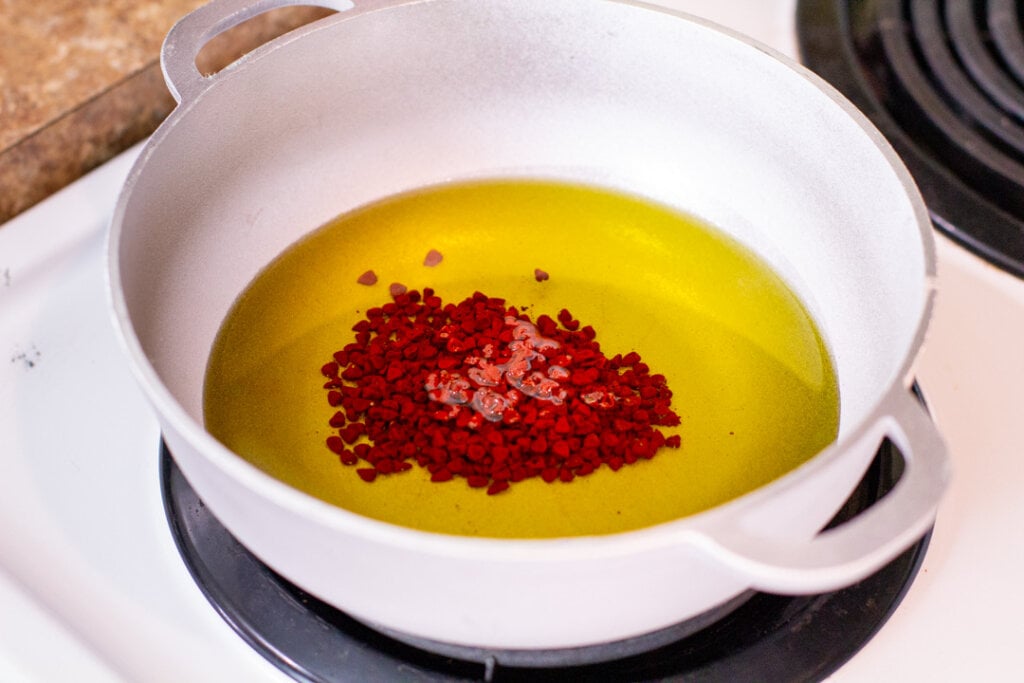 oil and annatto seeds in a small pan