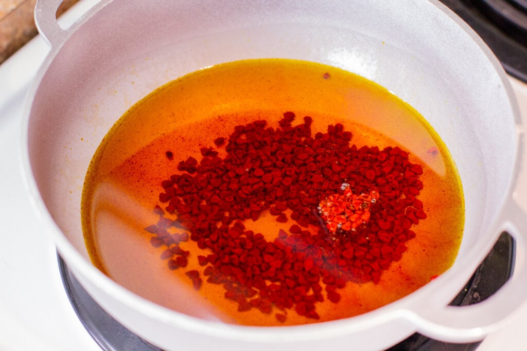 orange colored oil with annatto seeds in a pot