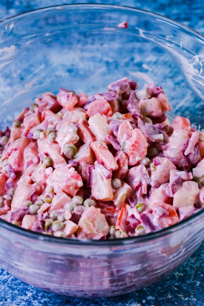 Russian potato salad in a glass mixing bowl